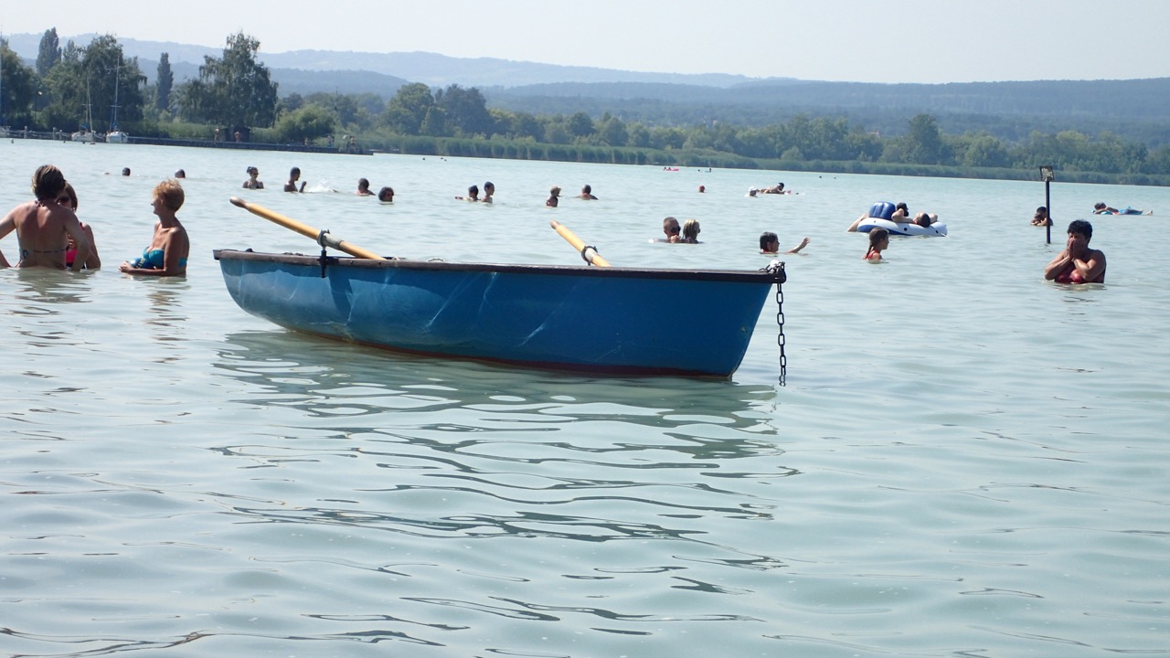 Barco azul e banhistas numa praia do lago Balaton