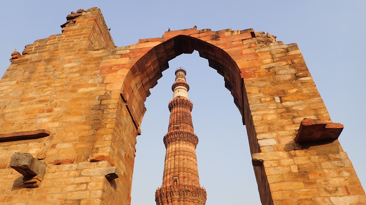 Qutb Minar enquadrado por um arco de pedra